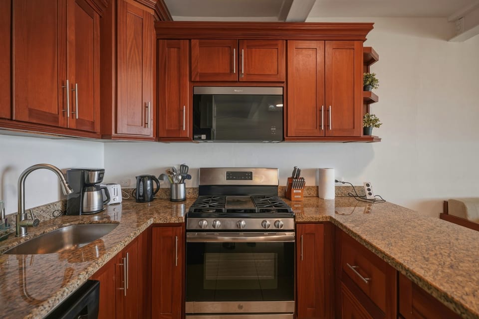 Fully equipped kitchen with side-by-side stainless fridge, built-in wine rack, gas range, microwave & granite counters. Everything you need for long stays — ideal for digital nomads & families at Kite Beach DR.