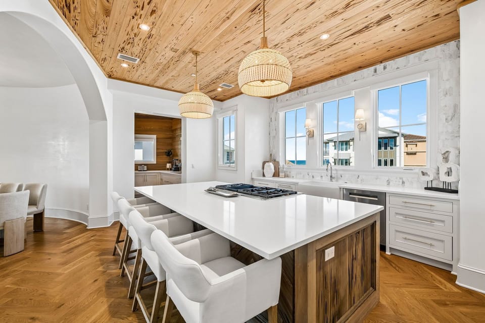 Gather with loved ones in this stunning kitchen with a spacious island, modern appliances, and warm wood accents beneath a beautiful natural wood ceiling. Sunlight pours through the windows as you cook and create.