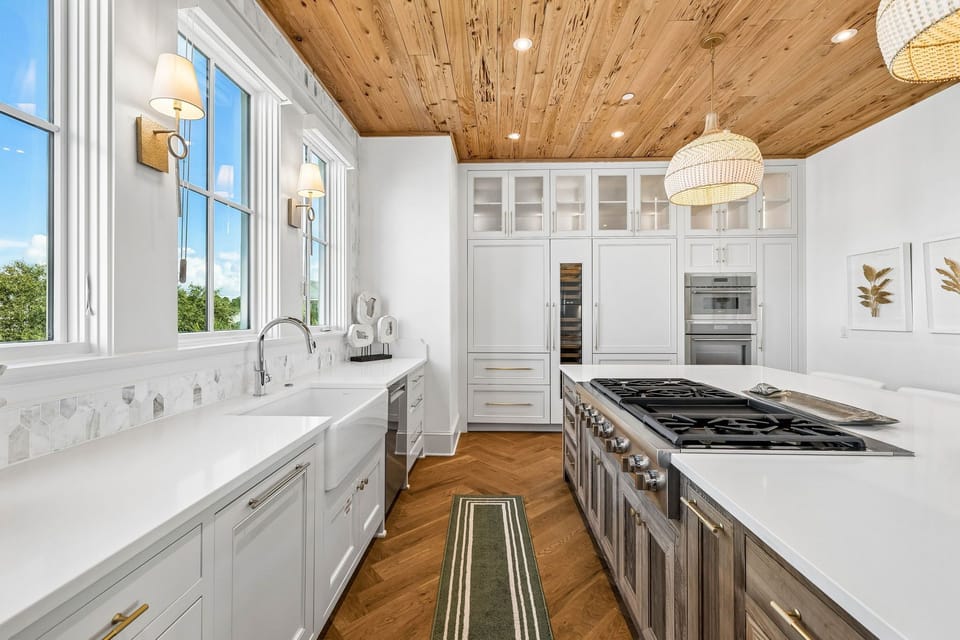 Picture yourself preparing meals in this sun-drenched kitchen with stunning wood ceilings and premium appliances. Natural light pours through expansive windows, illuminating sleek countertops and professional-grade cookware—your culinary haven awaits.