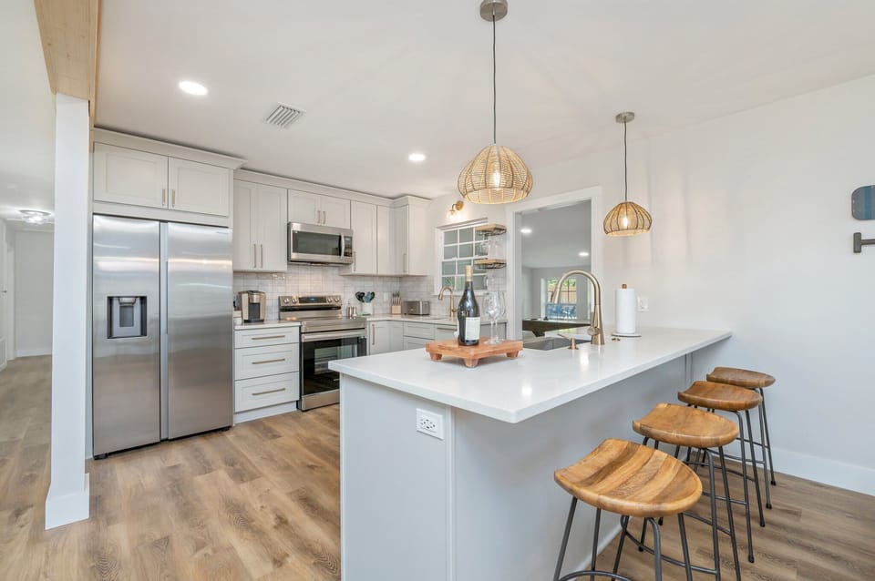 This modern kitchen is a chef's dream! Featuring stainless steel appliances, sleek white cabinetry, and a spacious island with stylish barstools, it’s the perfect hub for preparing meals and enjoying casual conversation with your group.