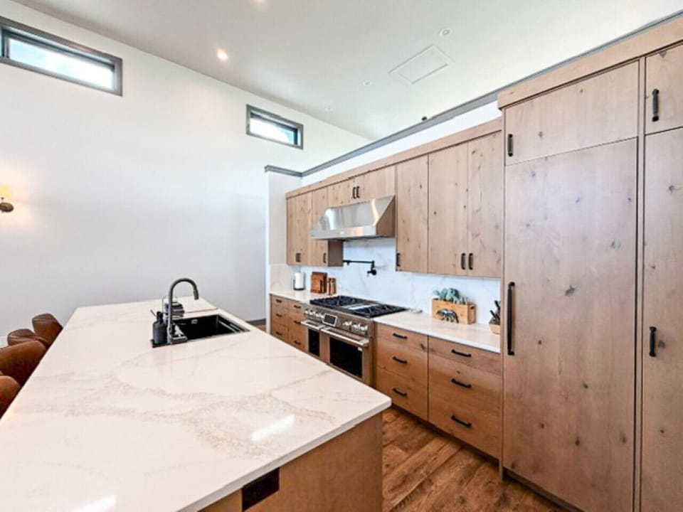 Sleek kitchen with quartz island, wood cabinetry, and clean contemporary design flooded with natural light