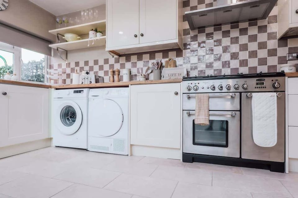 Modern kitchen with washer, oven, patterned backsplash, and clean finishes.