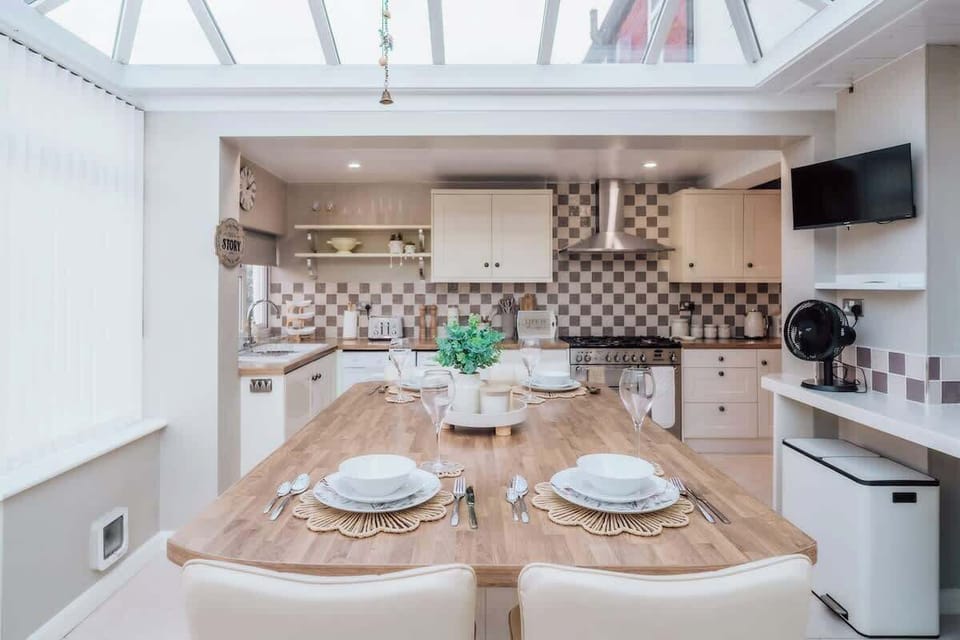 Stylish kitchen with skylight, patterned backsplash, and neatly arranged tableware.

