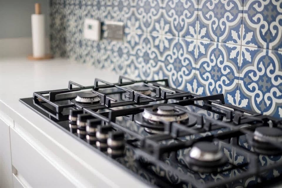 Close-up of gas stove with decorative patterned tile backsplash