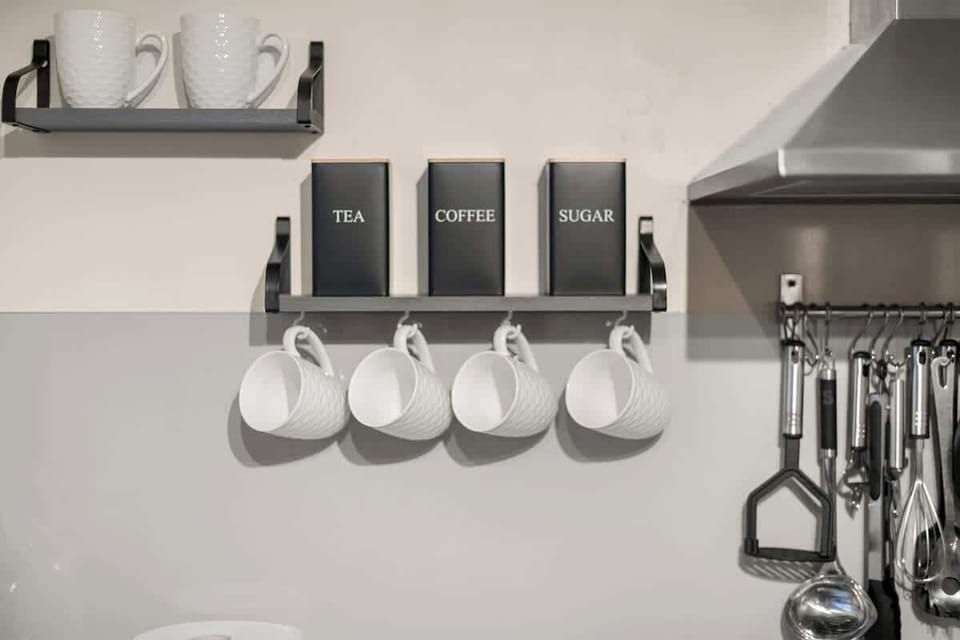 Organized kitchen shelf with mugs jars and simple decor accents
