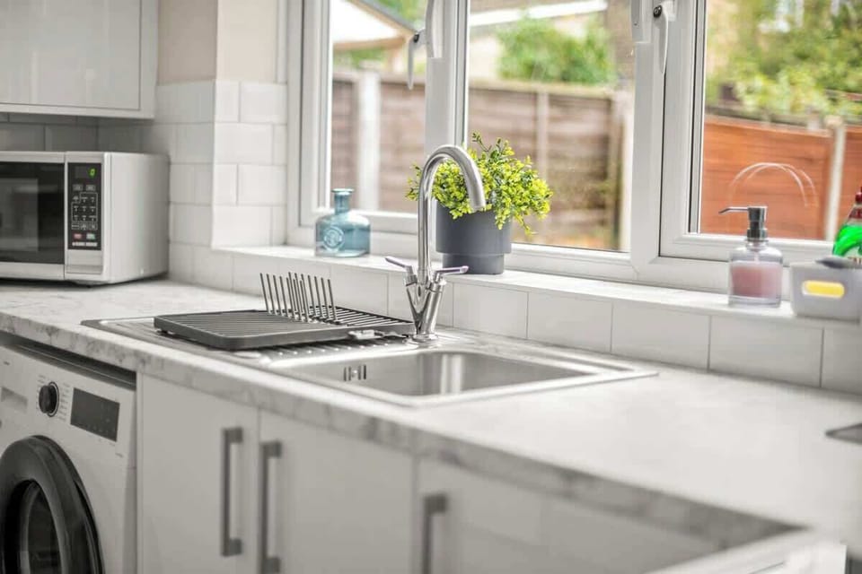 Kitchen sink area with window view, clean surfaces, and plants
