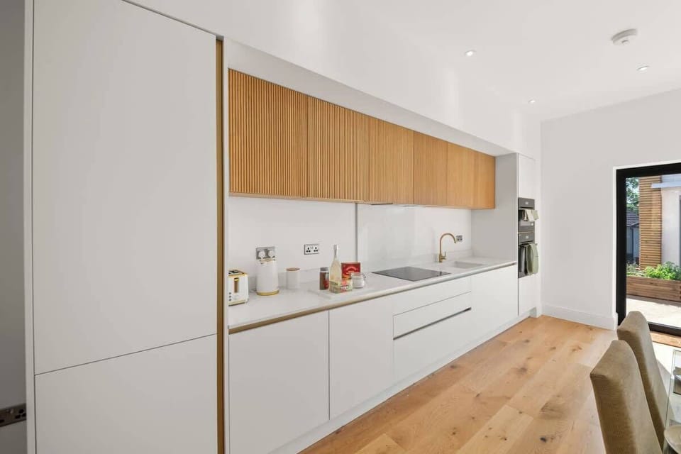 Long modern kitchen with integrated appliances, ample storage, bright finishes
