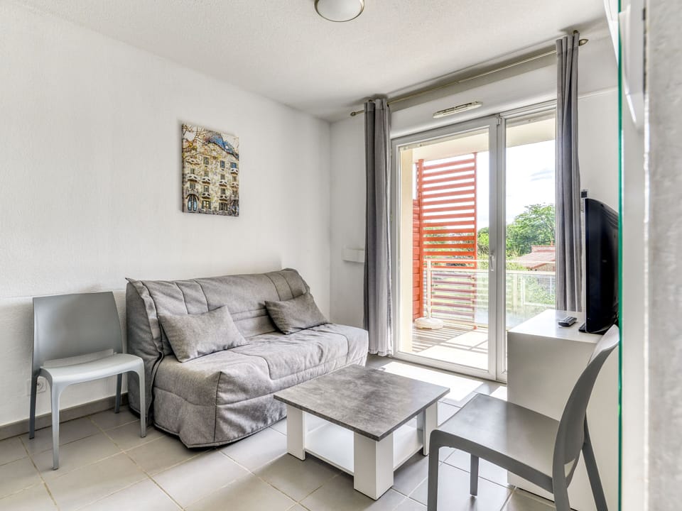 Living area with a double sofa bed and flat-screen TV — air conditioning keeps things cool