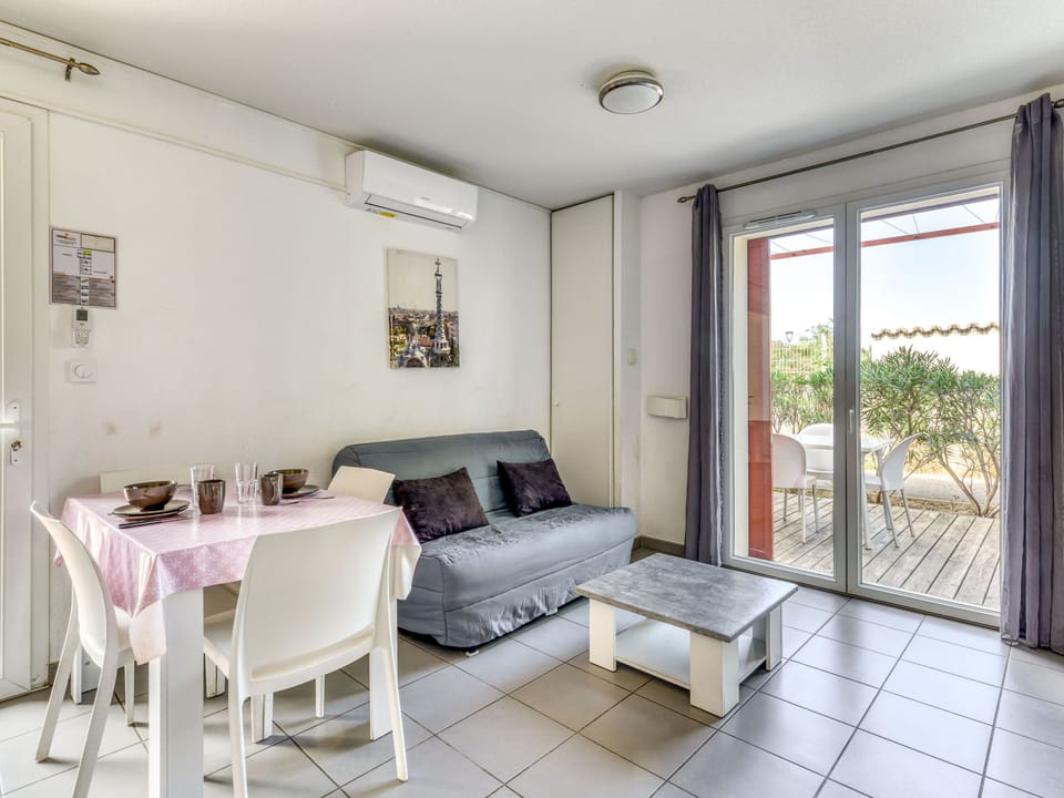 Open-plan living area with sofa bed and flat-screen TV leads straight out to the furnished terrace