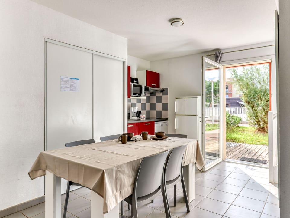 Kitchenette with red cabinetry, ceramic hob, microwave, and dishwasher — all the essentials