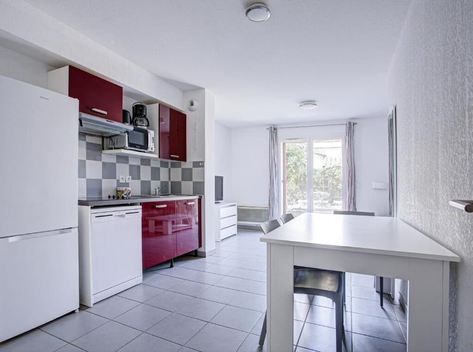 Red-cabinet kitchenette with ceramic hob, dishwasher, and coffee machine for home-cooked meals