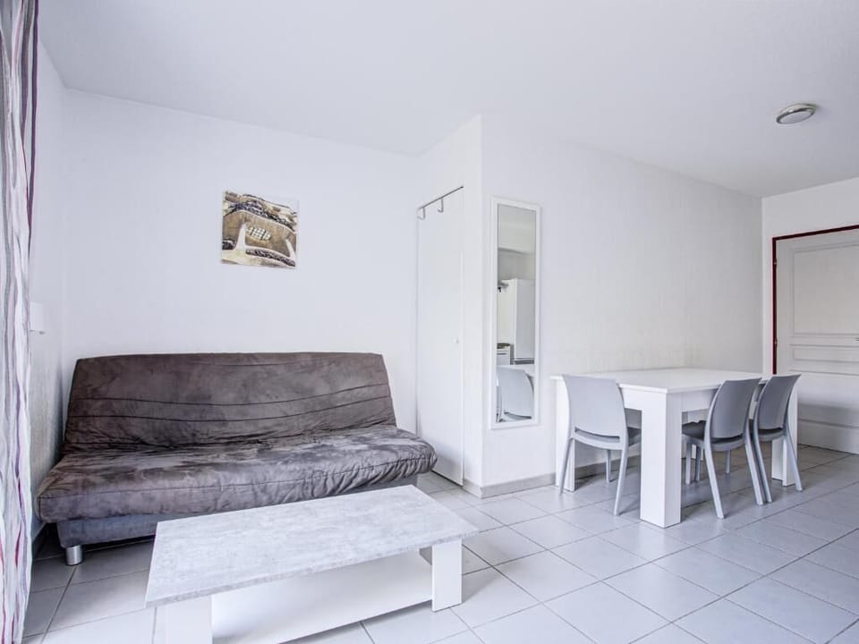 Living area with a double sofa bed, flat-screen TV, and air conditioning — pool access just outside