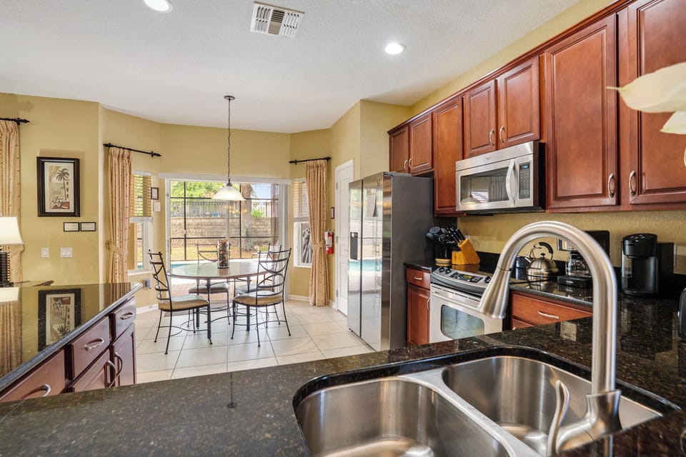 Modern kitchen with stainless steel appliances and a bright dining area overlooking the backyard.