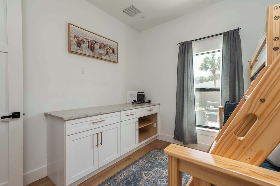 Natural light fills this cozy room featuring a wooden bunk bed and white cabinetry.