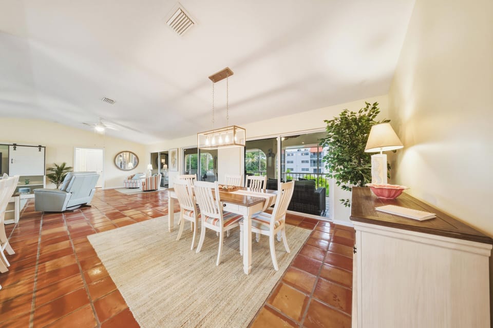 Enjoy waterfront dining with a large dining table and additional breakfast bar seating beside the open-concept kitchen. Located in a Marathon Florida Keys waterfront vacation rental with private pool and canal views.