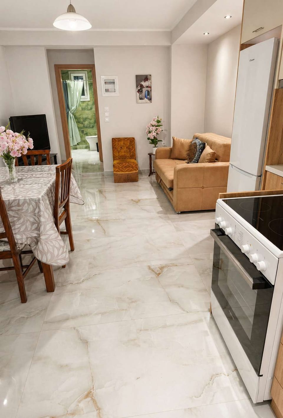 Bright open-plan kitchen and dining area with modern appliances, marble-style flooring, and a welcoming space ideal for enjoying home-cooked meals.