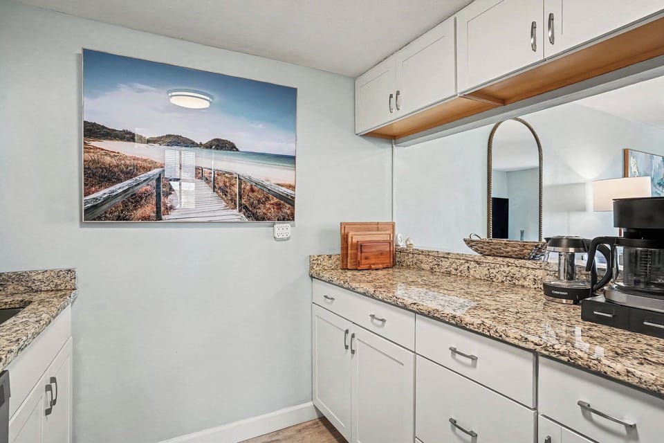 Modern coastal kitchen 🌊 Granite counters, white cabinets, and beautiful beach art. Fully stocked and ready for easy vacation meals.