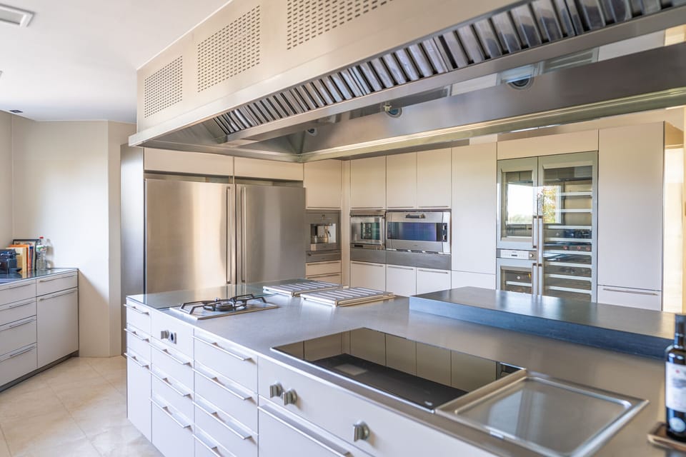 Majordoms Golf’s kitchen fits 15+ guests: five-burner hob, two full fridges, wine fridge, oven, Teppanyaki griddle, super-automatic coffee maker and tableware for 38.