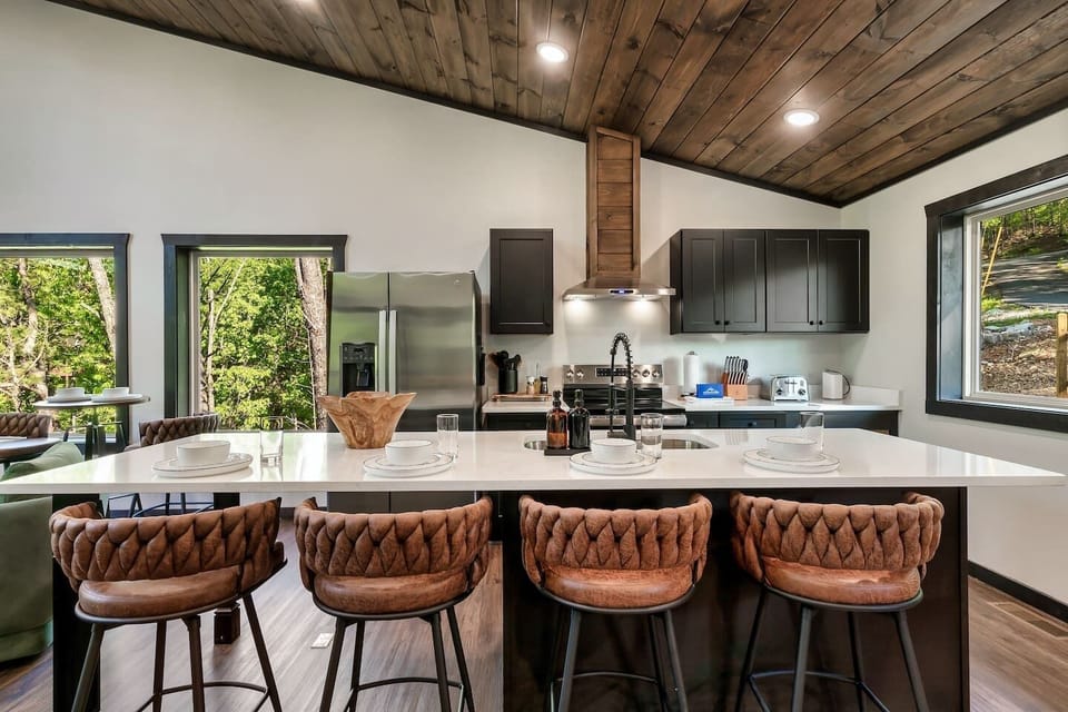 Fully equipped modern kitchen with quartz island, stainless steel appliances, and seating for four.