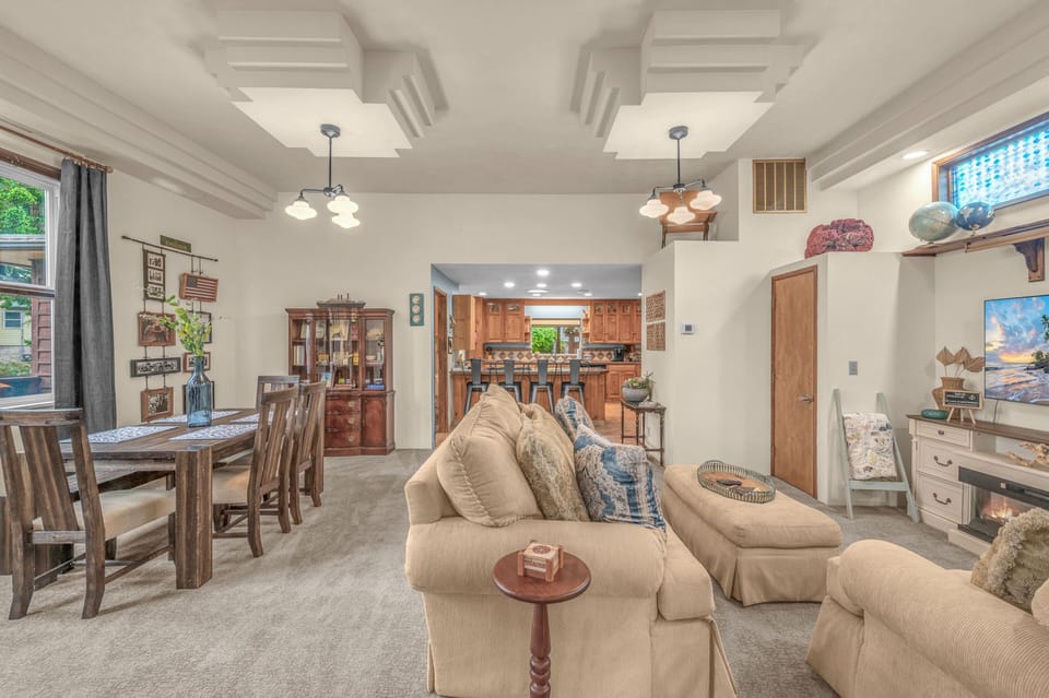 Picture yourself unwinding in this spacious living area, where soft carpets meet comfortable seating and sunlight streams through large windows. The open layout flows seamlessly into the dining space and kitchen, creating your ideal home-away-from-home.