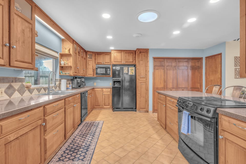 Your spacious, fully-equipped kitchen awaits with warm wood cabinetry, generous counter space, and modern appliances—perfect for whipping up meals during your stay.
