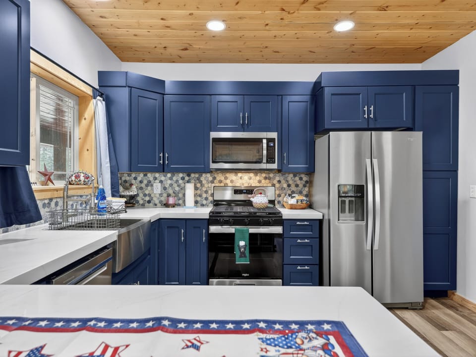Cook your favorite meals in this beautifully designed kitchen with navy cabinetry, stainless steel appliances, and warm wood ceilings that create a welcoming atmosphere for your stay.