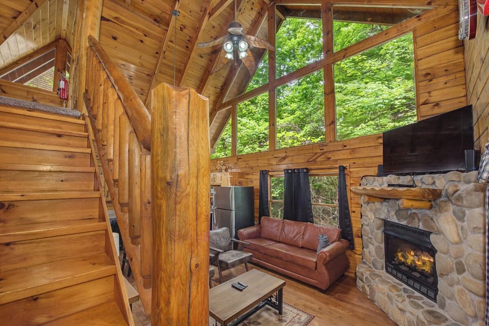 Unwind in your own rustic retreat with soaring ceilings, cozy fireplace, and lush forest views right outside towering windows that bathe the space in natural light.