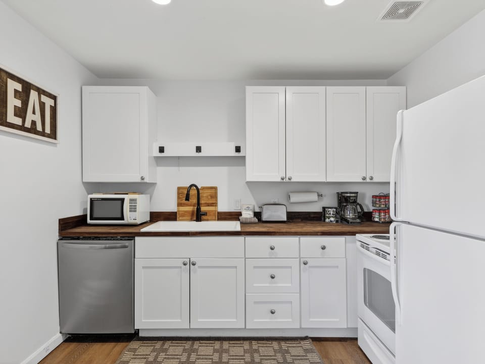 Your fully equipped kitchen features crisp white cabinetry, warm wood countertops, and everything you need to prepare meals during your stay—from the microwave and coffee maker to the stove and full-sized refrigerator.