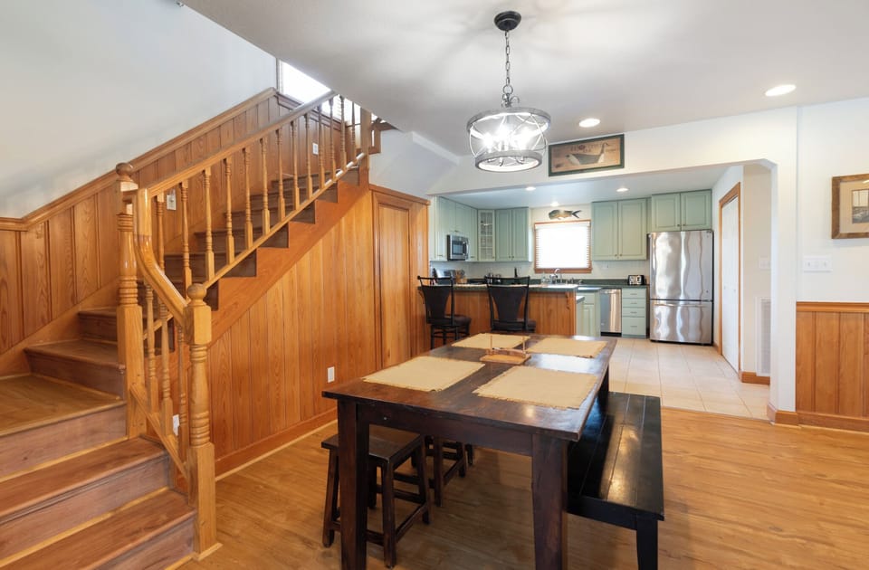 Step into your open-concept retreat where warm wood floors, a handcrafted dining table, and a fully-equipped kitchen await. Your home-away-from-home invites you to gather, cook, and create memories in comfort.