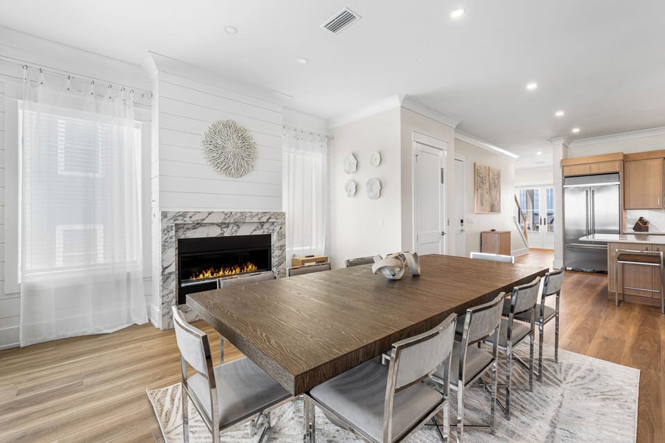 Gather around this elegant dining table for memorable meals with loved ones, warmed by the cozy fireplace and bathed in natural light from expansive windows.
