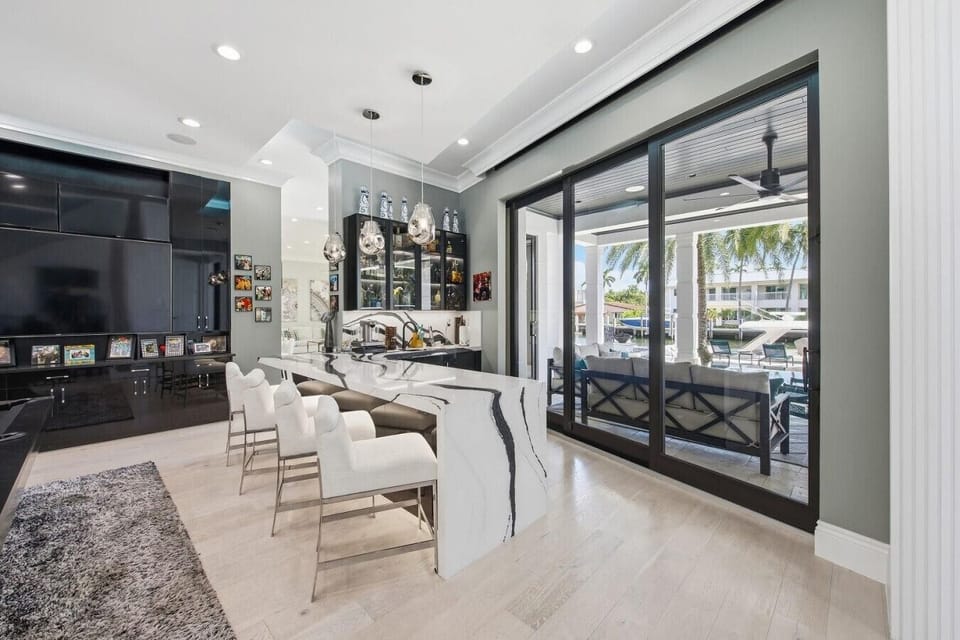 Modern wet bar featuring a waterfall marble counter, bar seating and patio access
