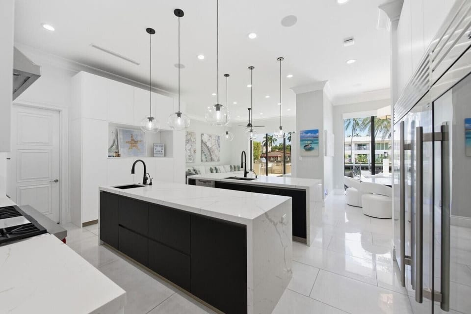 Expansive modern kitchen featuring dual marble islands, custom cabinetry and seamless flow into the living spaces
