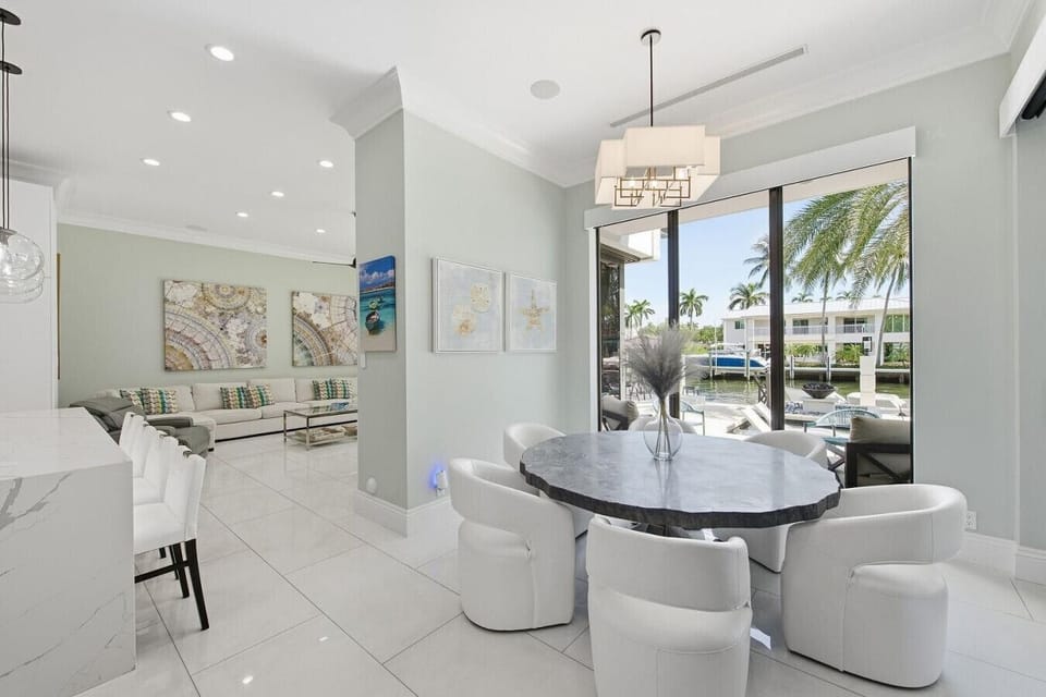 Bright casual dining area equipped with a round stone table, plush white seating and large windows