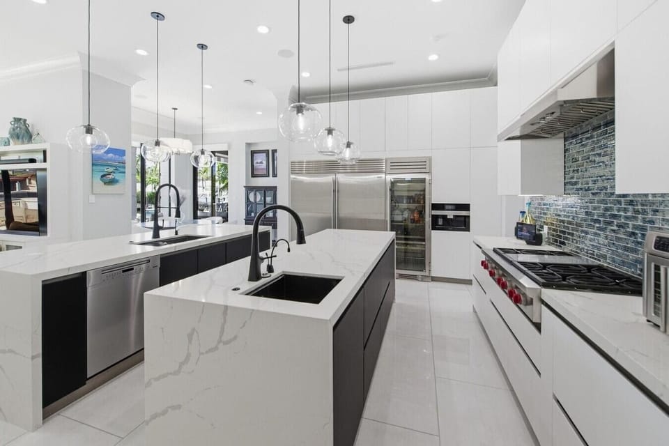 Expansive modern kitchen featuring dual marble islands, custom cabinetry and seamless flow into the living spaces