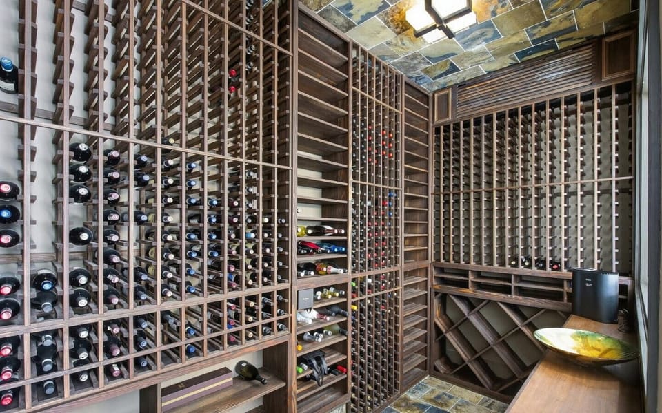 Custom walk-in wine cellar featuring extensive wooden bottle racks and a pouring counter