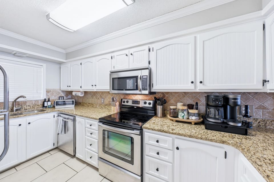 Bright kitchen with granite counters, stainless appliances, and coffee station