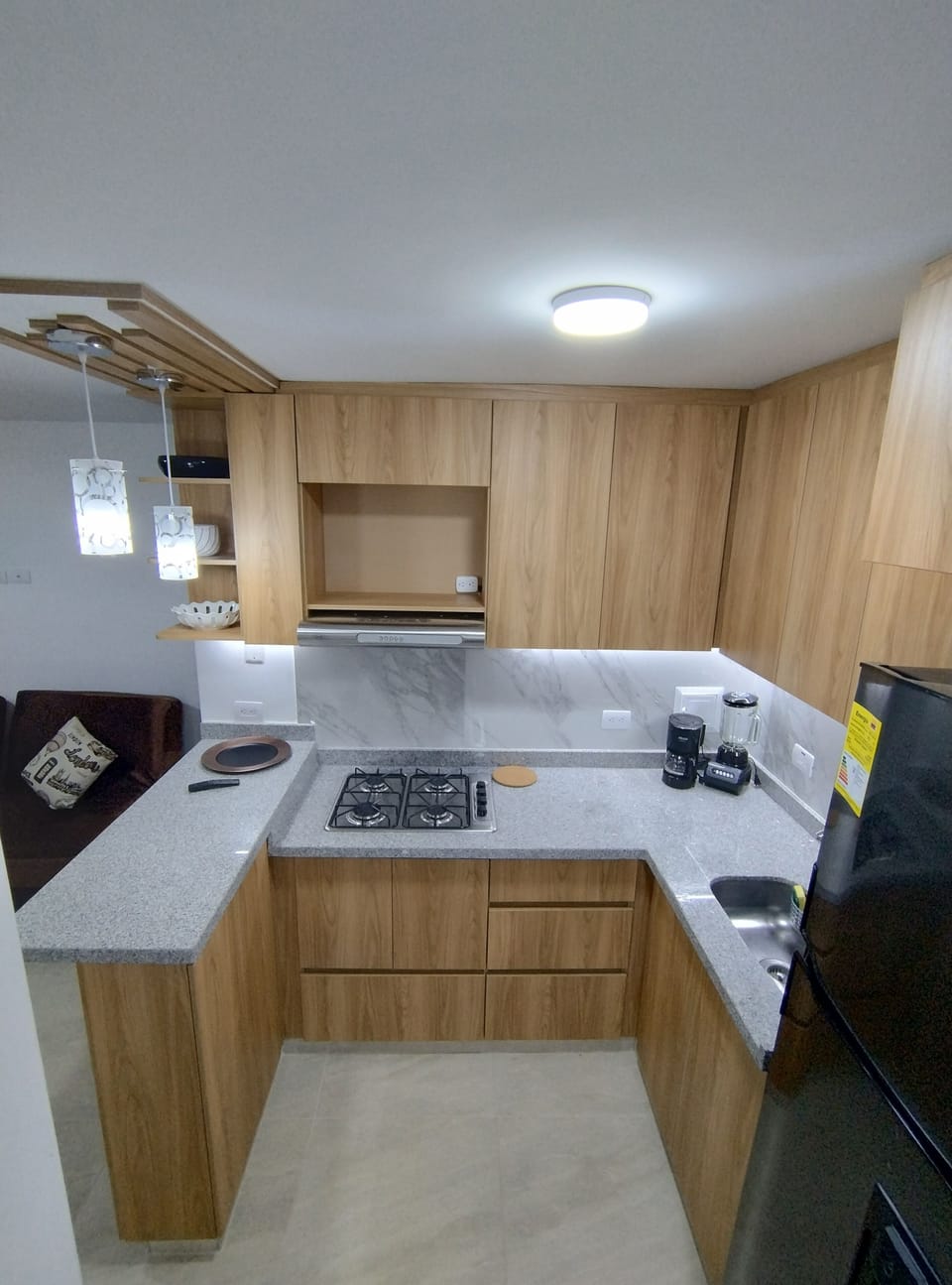 Modern full kitchen with stove, fridge, blender, and coffee maker.