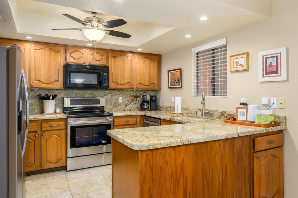 Granite countertops wrap the kitchen in a U-shape, paired with honey oak cabinets and stainless steel appliances.