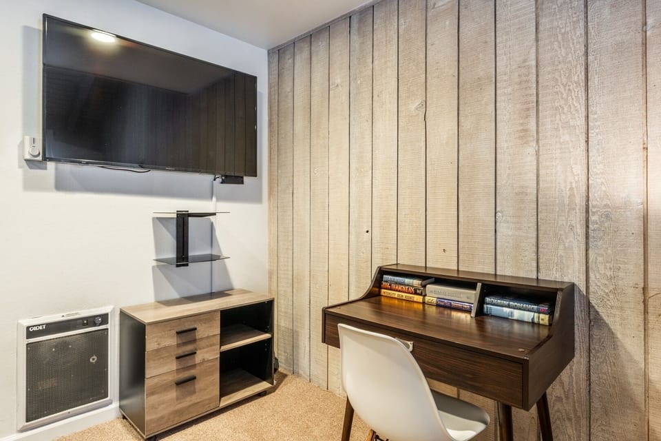 Cozy work nook with desk, wood accent wall, and wall-mounted TV