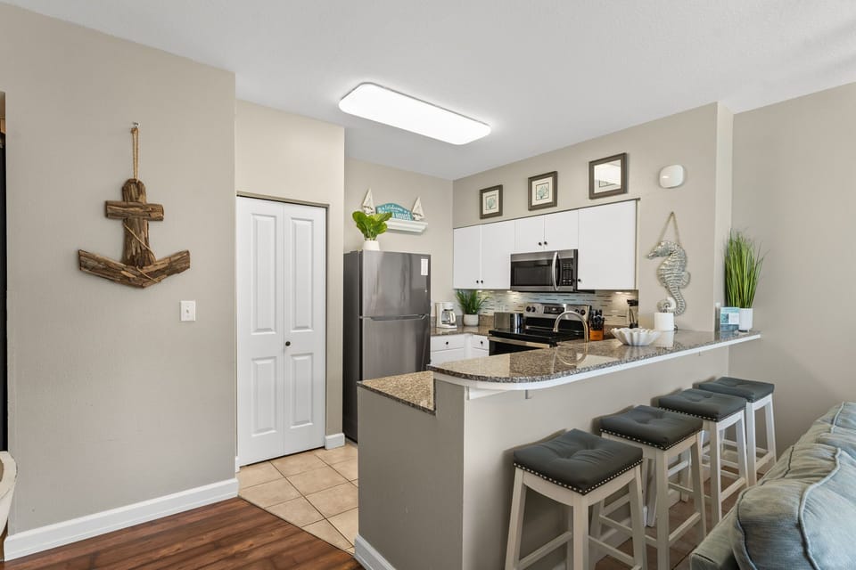 Kitchen with granite countertops, stainless steel appliances, and bar seating — perfect for easy meals, snacks, and morning coffee before heading to the beach.