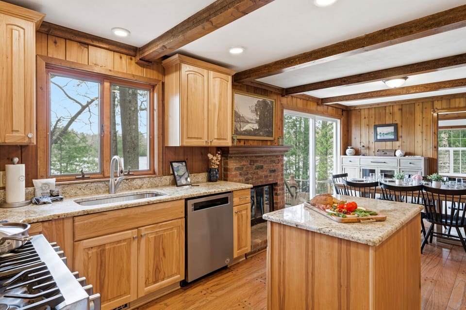 Warm wood kitchen with granite counters, island prep space, lake views, and an inviting dining area.