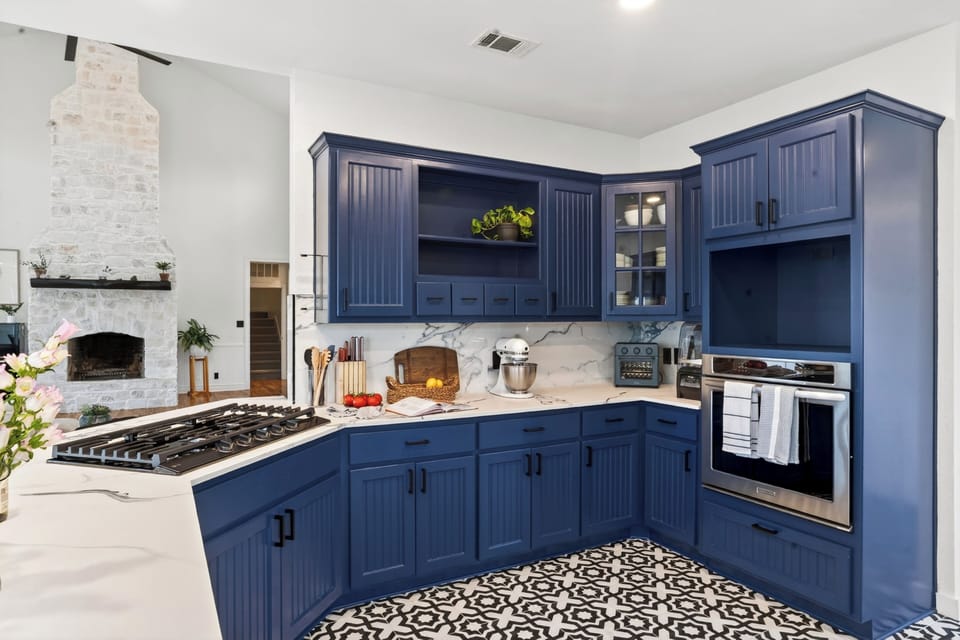 Cook, gather, and entertain in this designer kitchen featuring bold navy cabinetry, marble finishes, and spacious island seating.