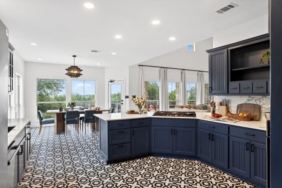 Cook, gather, and entertain in this designer kitchen featuring bold navy cabinetry, marble finishes, and spacious island seating.