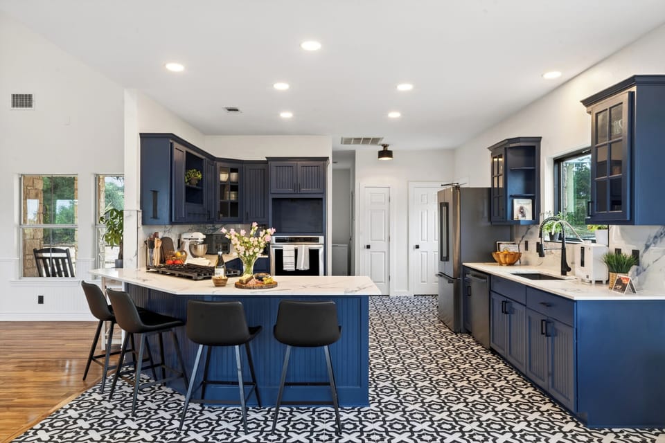 Gather around this designer kitchen featuring bold navy cabinetry, patterned tile floors, and a spacious island made for meals and conversation.
