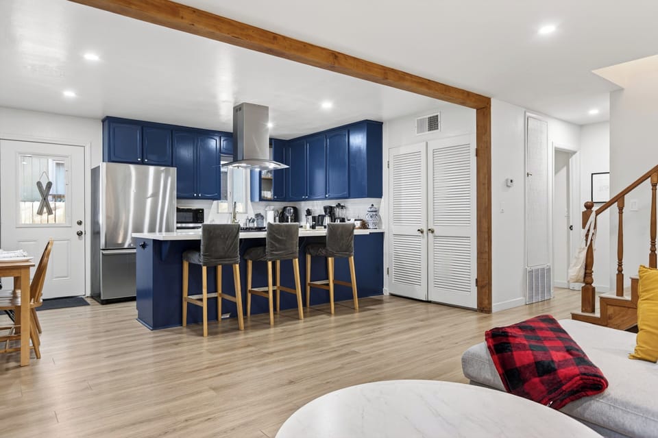 Gather around the bold blue kitchen with bar seating, stainless steel appliances, and an open layout designed for easy group living.
