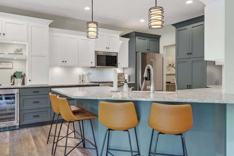 Gather around this spacious kitchen island with modern pendant lighting, granite countertops, and stainless-steel appliances. The blend of white and teal cabinetry creates a welcoming space for your vacation meals.