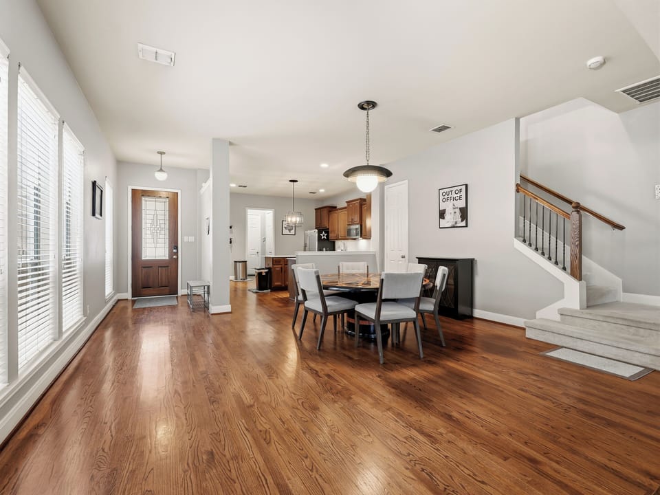 Step into your open-concept living space where gleaming hardwood flows from entry to dining, bathed in natural light from generous windows and softened by soaring ceilings that create an airy, welcoming atmosphere.
