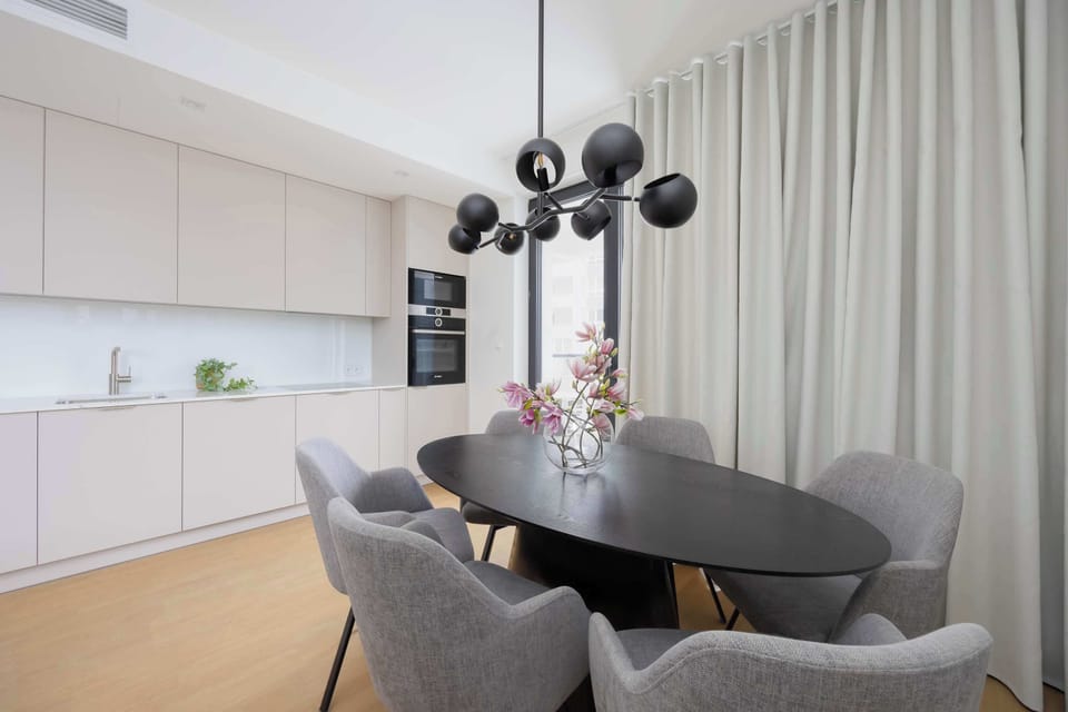 Contemporary dining space connected to a sleek fully equipped kitchen with modern finishes.