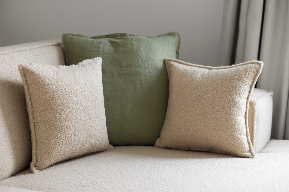 Soft decorative cushions in natural green and beige tones adding warmth and comfort to the interior.