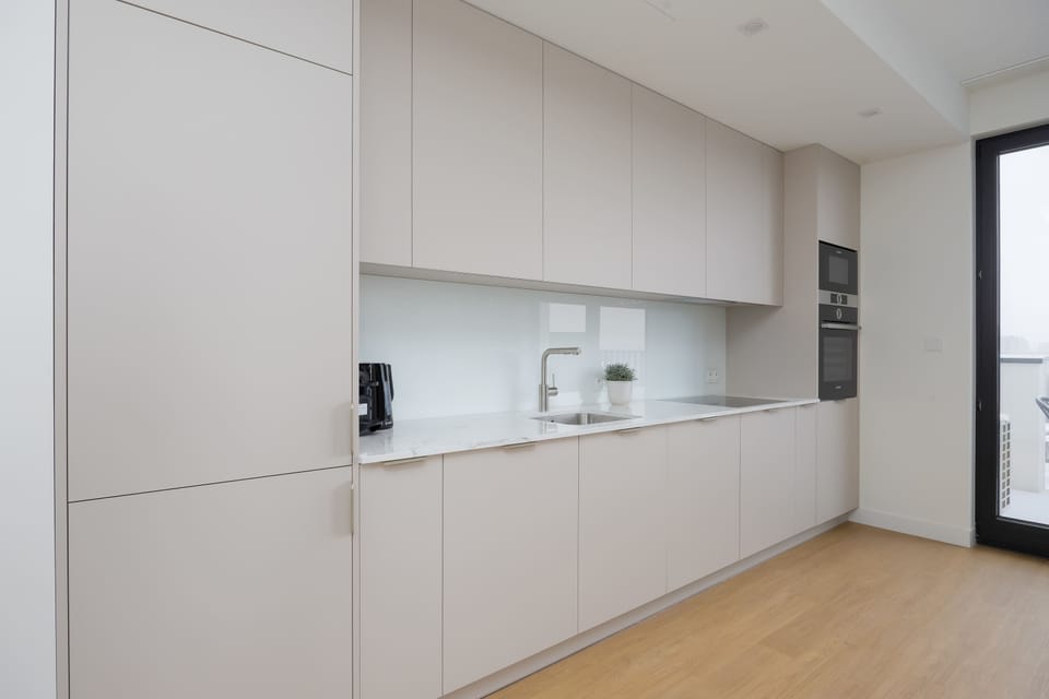 Bright minimalist kitchen with integrated appliances and elegant white cabinetry.